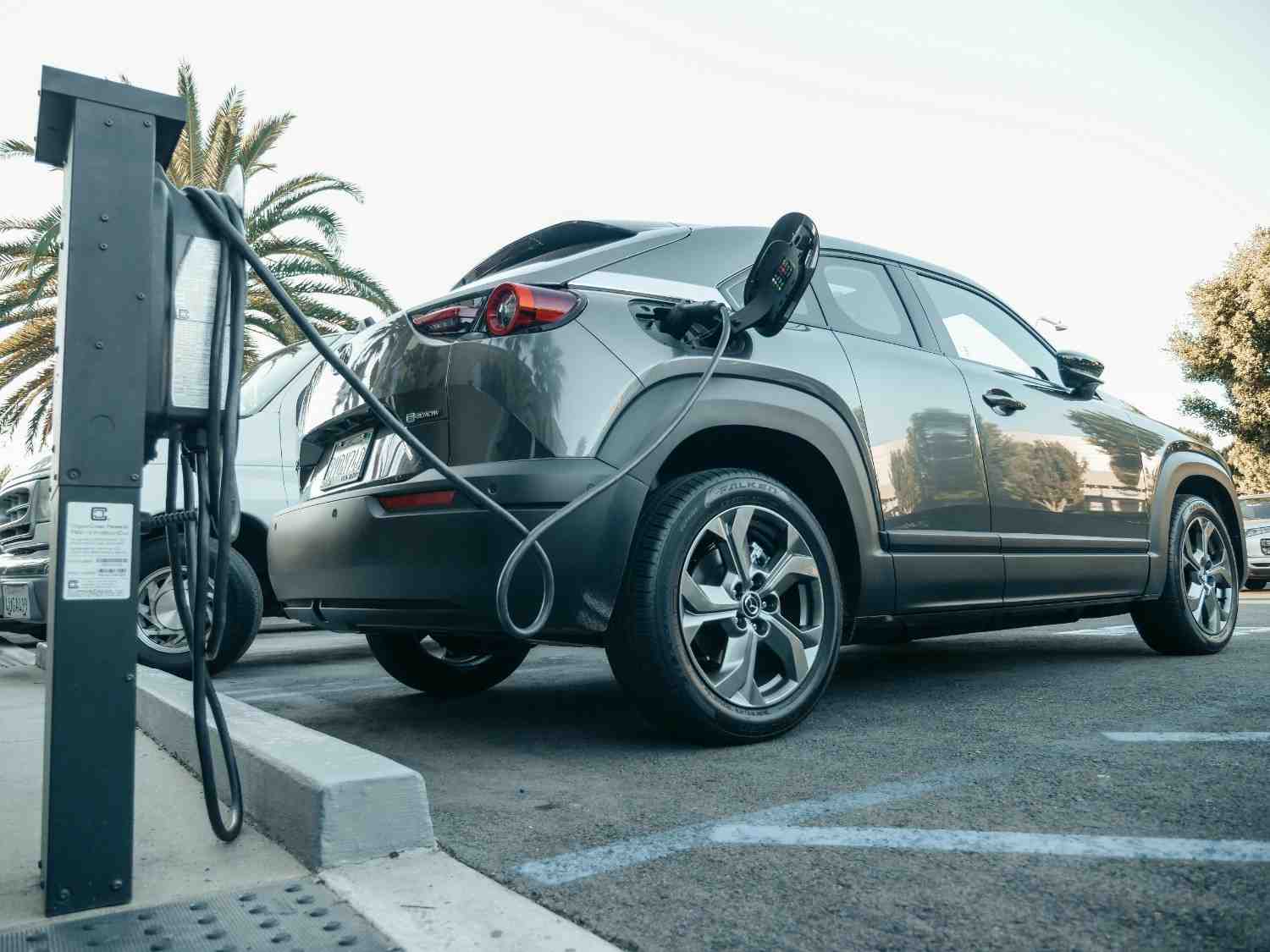A modern electric car being charged at a clean, futuristic station at sunrise